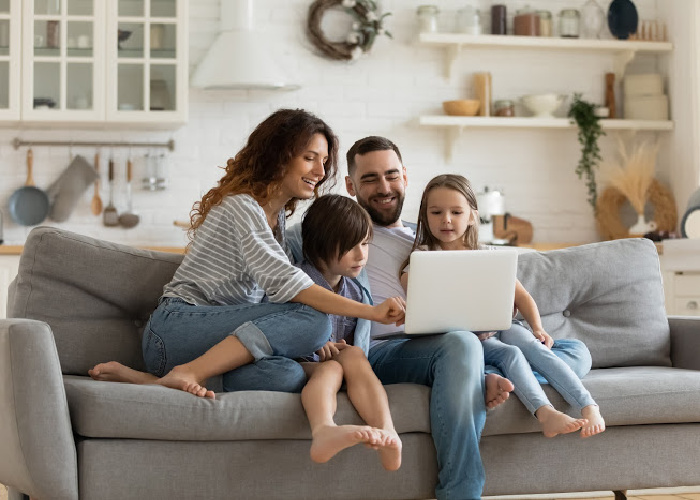 Family of four on couch looking at laptop