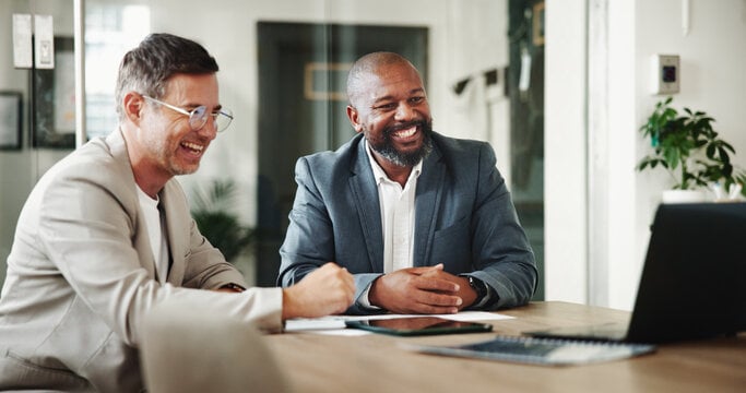 Two men seated at a conference table, discussing financial information at a meeting