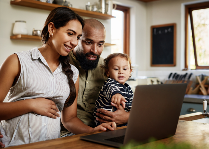 Family gathered together at home looking at information on a computer screen