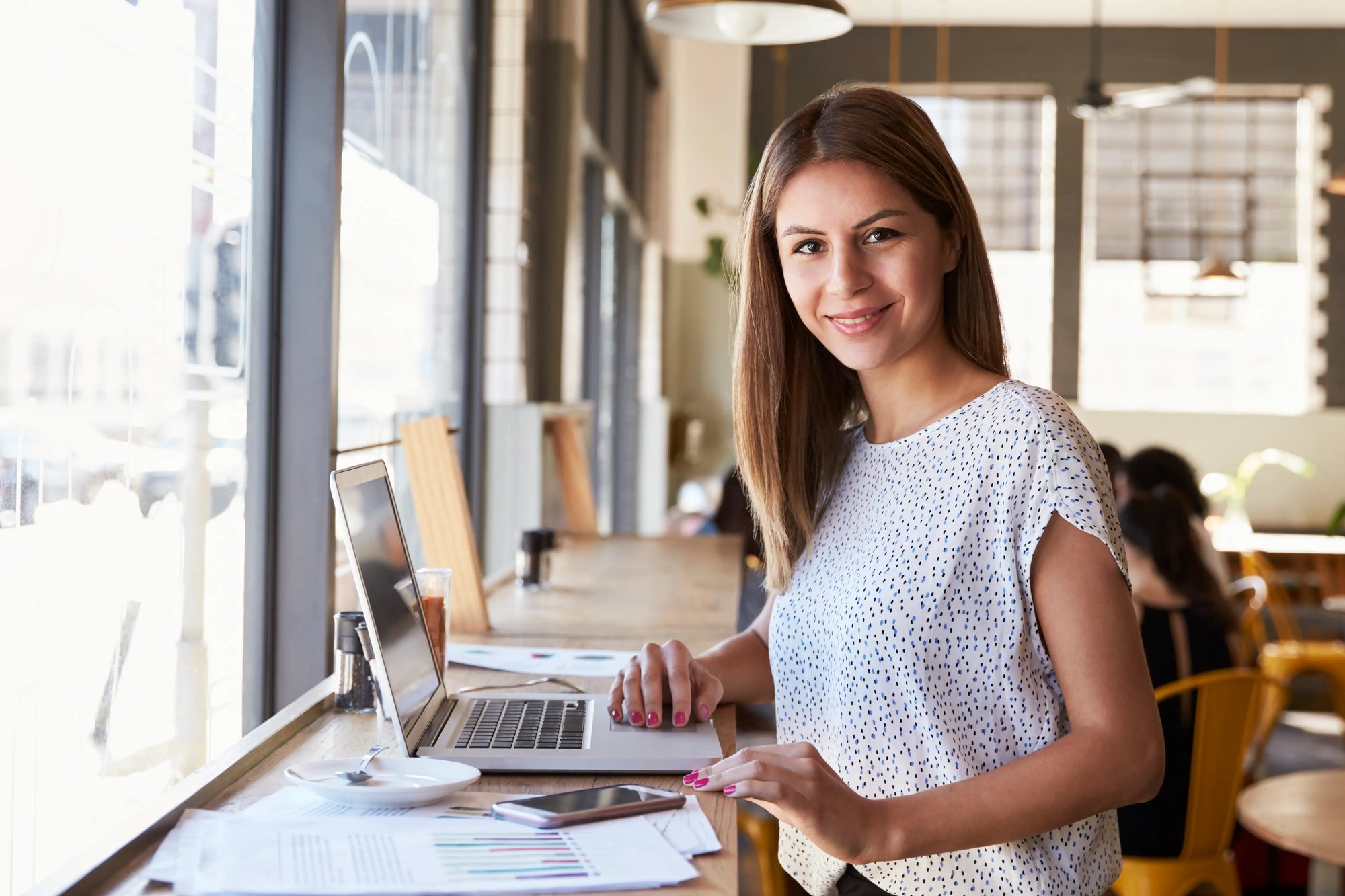 Woman smiling while working on her computer in a café