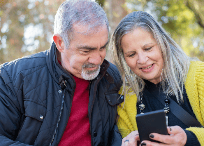 Older couple looking at a phone at an outdoor park.