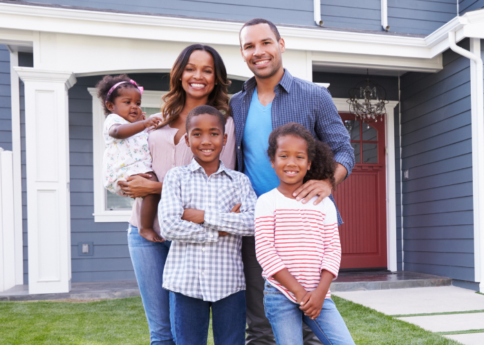 family-standing-in-fron-of-blue-house