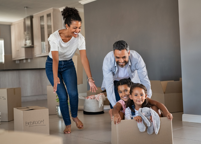 Young Family playing with cardboard boxes while moving into new home