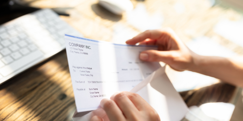 Person opening paycheck in envelope