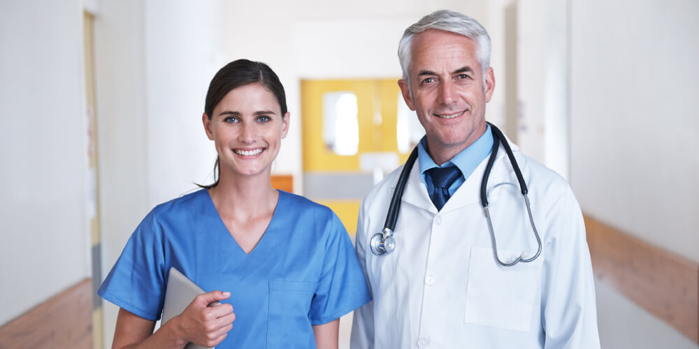 Nurse and doctor standing in hallway smiling