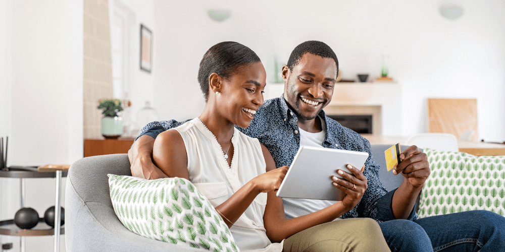 Couple looking at tablet and holding credit card