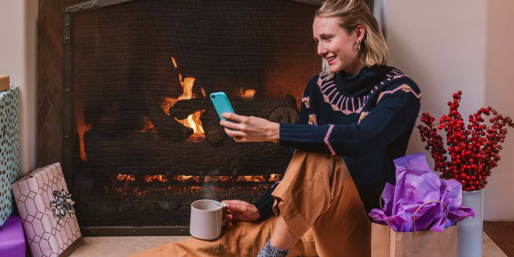 Woman using her phone in front of fireplace