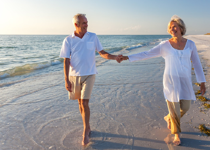 Older couple walking hand in hand on the beach